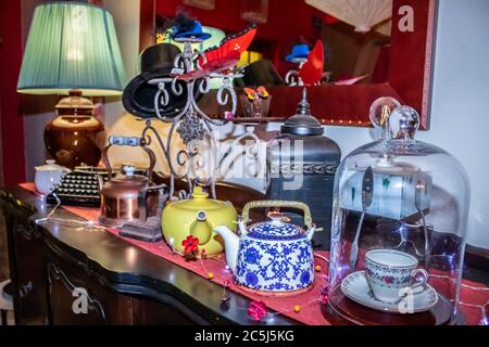 Bunte Tee-Party mit Tisch ausgelegt ausgefallene Dekorationen von Hüten, Teekannen und Ziervogel Käfig Stockfoto