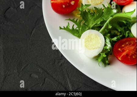 Caesar Salat mit Croutons, Wachteleiern, Kirschtomaten und gegrilltem Hähnchen in Holzplatte auf dunklem rustikalem Tisch Stockfoto