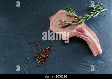 Rohes Stück Fleisch für Steaks, Knochenrippe mit Meersalz und Gewürzen auf dunkelblauem Hintergrund Draufsicht Stockfoto