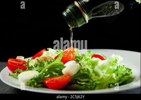 Salat mit Wachteleiern Rucola Salat und Kirschtomaten gegossen Oliven-Olysen auf schwarzem Hintergrund Stockfoto
