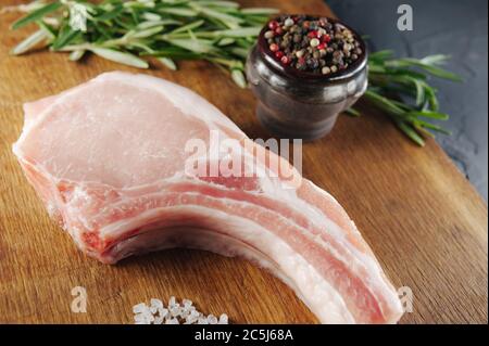 Ein schönes Stück rohes Fleisch mit Gewürzen auf einem Holzbrett mit Salz und Pfeffer Stockfoto