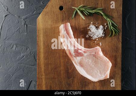 Top Aussicht rohes Kotelett Steak und Knoblauch, Pfeffer auf hölzernen Hintergrund. Stockfoto