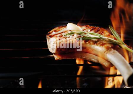 Gekochtes Steak mit Backform auf einem Grill mit Feuer auf schwarzem Hintergrund mit einem Platz für Text und Inschriften. Nahaufnahme Stockfoto