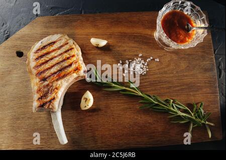 Abendessen für echte Mann gegrilltes Steak auf dem Knochen mit Backen und Knoblauch und grobes Salz auf einem Holzbrett Stockfoto