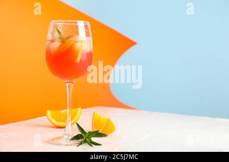 Komposition mit aperol Spritz Cocktail auf farbigem Hintergrund. Sommergetränk Stockfoto