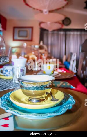 Bunte Tee-Party mit Tisch ausgelegt Phantasie Teetassen und Untertassen, mit süßen und herzhaften Speisen auf Platten Stockfoto