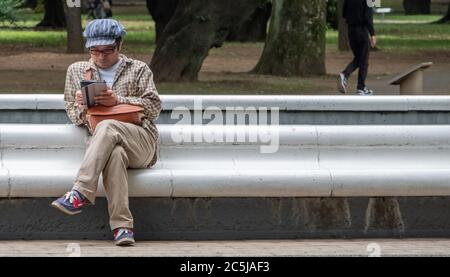 Mann liest ein Buch im Yoyogi Park, Tokio, Japan Stockfoto