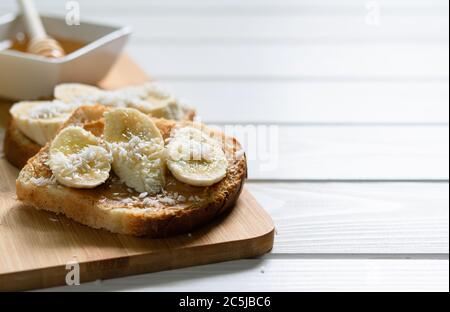 Fast Food, Snack, Erdnussbutter, Banane und Honig Sandwich auf einem weißen Holztisch, freier Platz zum Schreiben von Text Stockfoto