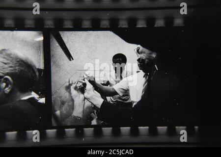 Feine 70er Jahre Vintage Kontakt Print schwarz-weiß Fotografie einer Gruppe von Mitarbeitern diskutieren Strategie zur Lösung eines Problems. Stockfoto