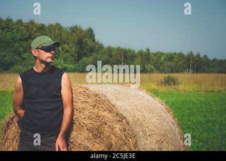 Mann, der vor einem Heuballen steht, sonnige Sommeransicht Stockfoto