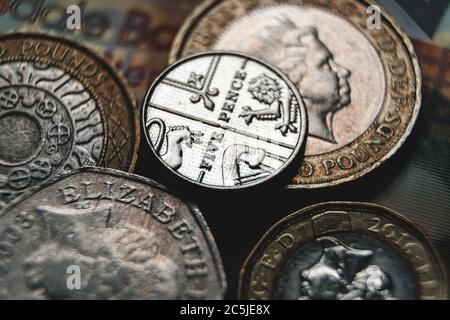 Einige britische Münzen auf einem 10-Pfund-Schein organisiert zeigte in einer Nahaufnahme Makro-Foto. Stockfoto