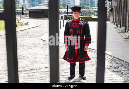 Ein Yeoman Warder hinter den verschlossenen Toren des Tower of London, der sich darauf vorbereitet, am 10. Juli für Besucher wieder zu öffnen, da weitere Sperrbeschränkungen in England aufgehoben werden. Stockfoto