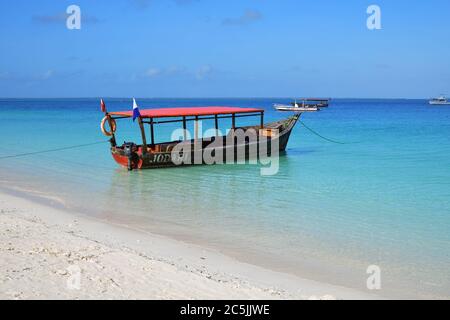 Sansibar, Tansania - 06. Oktober 2019: Weißer Sand, blaues transparentes Wasser und Motorboot, der im Indischen Ozean, Kendwa Strand, Afrika, festgemacht ist Stockfoto