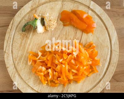 Paprika in Scheiben geschnitten auf einem Holzbrett. Draufsicht, oranges Gemüse. Stockfoto