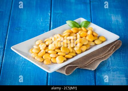 Lupini in weißem Teller auf rustikalem Tisch Stockfoto