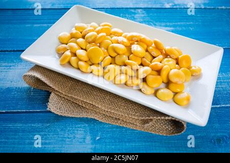 Lupini in weißem Teller auf rustikalem Tisch Stockfoto