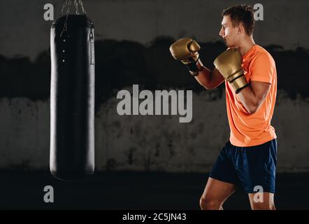 Junge Muskel Boxer mit einem Boxsack in der Turnhalle. Boxer schlagen Stanzgeschwindigkeit Tasche Stockfoto