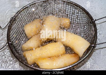 Waschen von Manihot mit Wasser in einem Metallsieb, Manihot esculenta. (Cassava roh Knolle). Maniok, auch Mandioca, Yuca, Balinghoy, mogo, Mantoca genannt Stockfoto