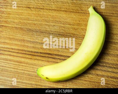 Eine einzelne reife gelbe Banane auf einem Holzhackbrett mit Kopierraum Stockfoto