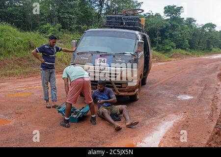Fahrer repariert zerbrochenen Minibus im Regenwald entlang der Linden-Lethem Schotterstraße, die Lethem und Georgetown, Guyana, Südamerika verbindet Stockfoto
