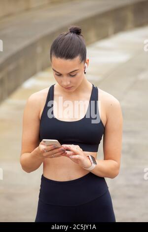 Eine sportliche Frau in Sportkleidung mit einem Mobiltelefon Stockfoto