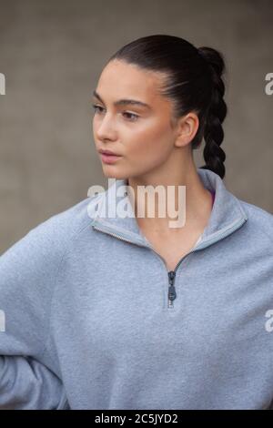 Porträt einer sportlichen jungen Frau mit Pferdeschwanz und grauem Sweatshirt Stockfoto