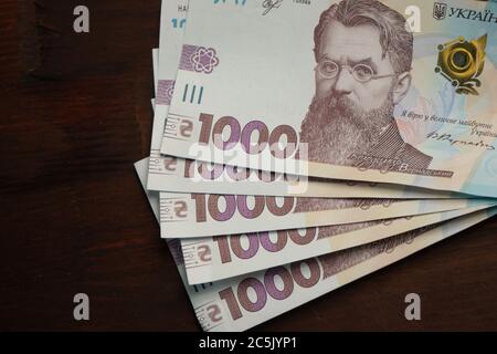 Packung der neuen ukrainischen Papierbanknoten Nennwert tausend Griwna auf Holzrücken. Kopieren Sie den Takt nach links. Nahaufnahme Stockfoto