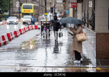 Glasgow, Schottland, Großbritannien. Juli 2020. Im Bild: Buchanan Street Shopping-Bereich mit Käufern trotzen dem strömenden Regen mit Regenschirmen und Gesichtsbezügen, die am 10. Juli nächste Woche obligatorisch werden. Quelle: Colin Fisher/Alamy Live News Stockfoto