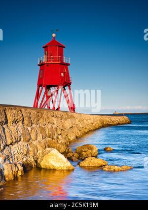 Blick entlang der Felspier in Richtung des roten Leuchtturms in South Shields an einem frühen Sommerabend Stockfoto