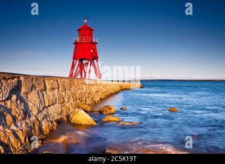 Blick entlang der Felspier in Richtung des roten Leuchtturms in South Shields an einem frühen Sommerabend Stockfoto