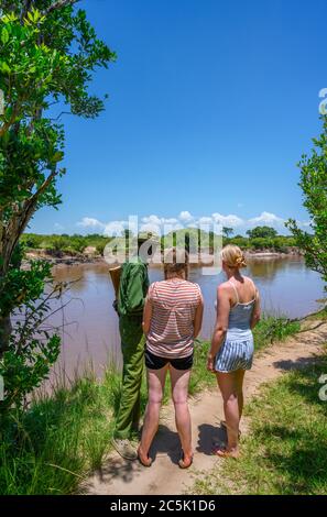 Touristen und Park Ranger Blick auf Nilpferde und Krokodile in der Mara River, Mara Dreieck, Masai Mara National Reserve, Kenia, Ostafrika Stockfoto