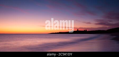 Farbenprächtiger Sonnenaufgang an einem kühlen Herbstmorgen mit Blick auf die Küste bis zum Dunstanburgh Castle. Stockfoto