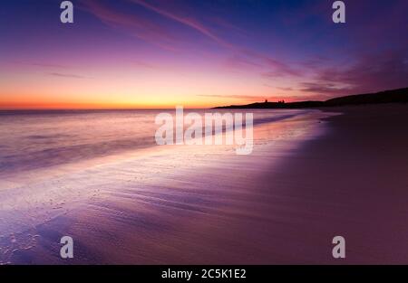 Farbenprächtiger Sonnenaufgang an einem kühlen Herbstmorgen mit Blick auf die Küste bis zum Dunstanburgh Castle. Stockfoto