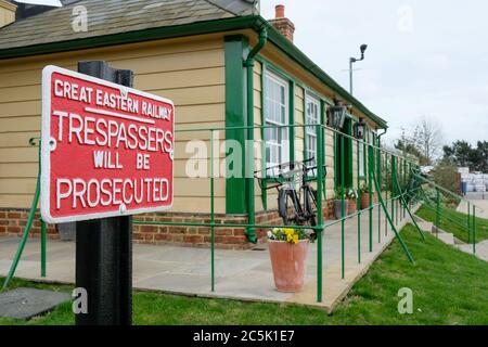 Altes Eisen No Trespassing Schild vor einem alten, alten, alten malerischen Bahnhof. Zeigt einen Teil des Buchungsbüros, frisch gestrichen. Stockfoto