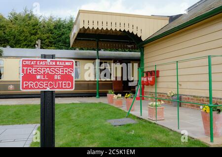 Altes Eisen No Trespassing Schild vor einem alten, alten, alten malerischen Bahnhof. Zeigt einen Teil des Buchungsbüros, frisch gestrichen. Stockfoto