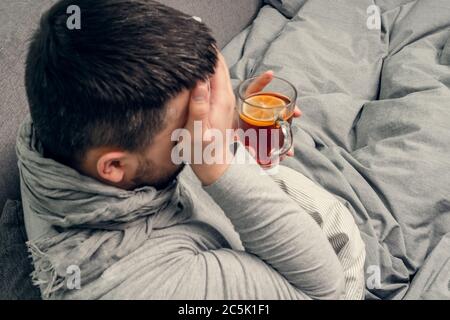 Krankheit. Zu Hause erfreuen. Ein junger Mann ist krank, ist zu Hause behandelt. Bläst ihre Nase in eine Serviette, laufende Nase. Infektion, Epidemie, Bacillus Träger. Stockfoto