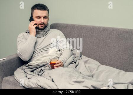Krankheit. Zu Hause erfreuen. Ein junger Mann ist krank, ist zu Hause behandelt. Bläst ihre Nase in eine Serviette, laufende Nase. Infektion, Epidemie, Bacillus Träger. Stockfoto