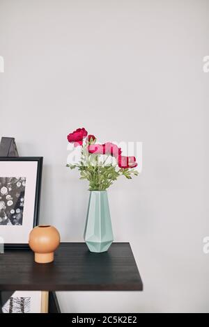 Rote Blume steht in einer blauen Vase auf dem Tisch.Interieur Detail. Stockfoto