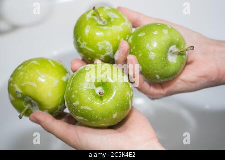 Obst waschen. Mädchen wäscht Äpfel. Hände und seifigen grünen Apfel Stockfoto