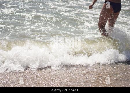 Kaukasische Person im Meer. Wellen Rollen auf einen Sandstrand. Urlaubskonzept. Tourismuskonzept Stockfoto