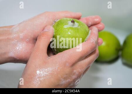 Obst waschen. Mädchen wäscht Äpfel. Hände und seifigen grünen Apfel Stockfoto