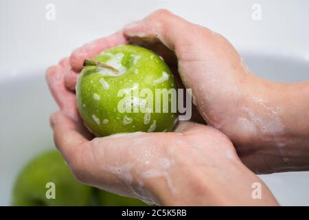 Obst waschen. Mädchen wäscht Äpfel. Hände und seifigen grünen Apfel Stockfoto