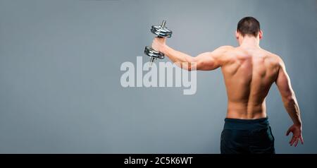 Rückansicht eines jungen männlichen Bodybuilders tun schwere Gewichts Übung mit Hanteln mit Kopieplatz Stockfoto