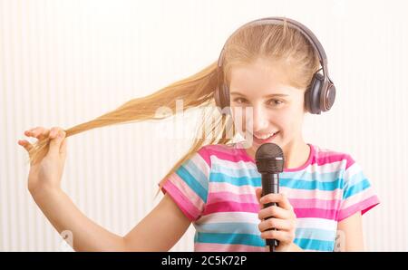 Lächelndes Mädchen in Kopfhörern hält Mikrofon im Studio Stockfoto