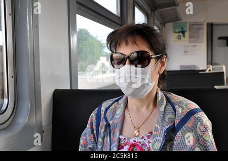 Eine Frau in einer medizinischen Schutzmaske reitet im öffentlichen Verkehr. Das Konzept des Schutzes gegen Atemwegsinfektionen, einschließlich Coronavirus Stockfoto