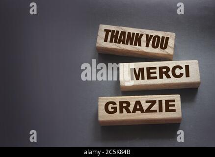 Text Danke Merci Grazie auf Holzblöcken auf schwarzem Hintergrund. Dankbarkeit ausgedrückt in Englisch fFranzösisch und Italienisch State of Mind Konzept Stockfoto
