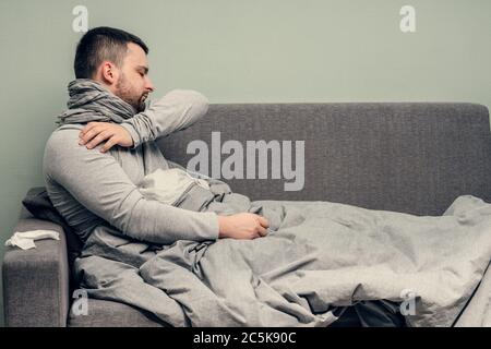 Krankheit. Zu Hause erfreuen. Ein junger Mann ist krank, ist zu Hause behandelt. Bläst ihre Nase in eine Serviette, laufende Nase. Infektion, Epidemie, Bacillus Träger. Stockfoto