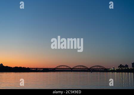 Silhouette der Eisenbahnbrücke über den Dnjepr. Sonnenuntergang über dem Dnipro River. August 2019. Kiew, Ukraine. Stockfoto