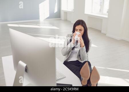 Entspannende Geschäftsfrau genießen Kaffee am Arbeitsplatz im Büro Stockfoto