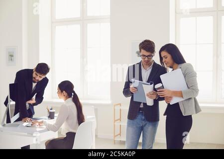 Geschäftsleute, die mit Diskussionen beschäftigt sind, analysieren Projektrisiken am Arbeitsplatz in modernen White Office. Stockfoto